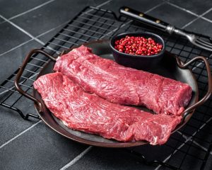 Lamb tenderloins raw on a tray with some herbs/spices